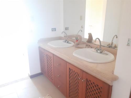 two sinks in a bathroom with two mirrors at PENTHOUSE EN PLAYA EL AGUA in Los Cerritos