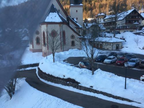 a church with cars parked in a parking lot covered in snow at Haus Silberdistel in Todtmoos