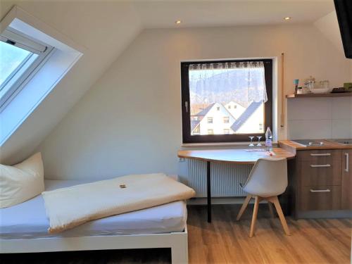 a bedroom with a bed and a desk and a window at Gästehaus Hermine in Oberkirch