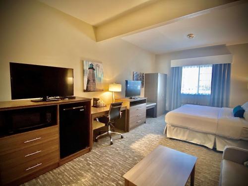 ein Hotelzimmer mit einem Bett und einem Schreibtisch mit einem TV in der Unterkunft Best Western Brockport Inn & Suites in Brockport