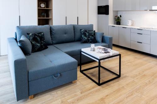 a blue couch and a coffee table in a living room at Downtown Apartments ,next to Spodek-free parking in Katowice