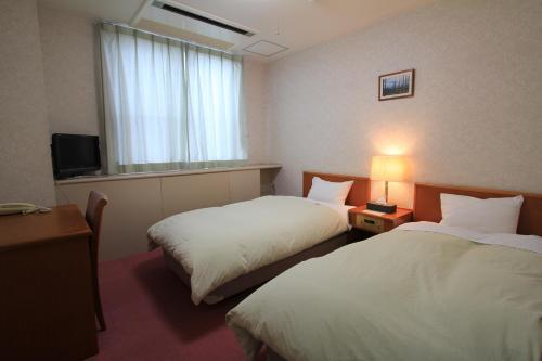 a hotel room with two beds and a window at Osaka International Youth Hostel in Takaishi
