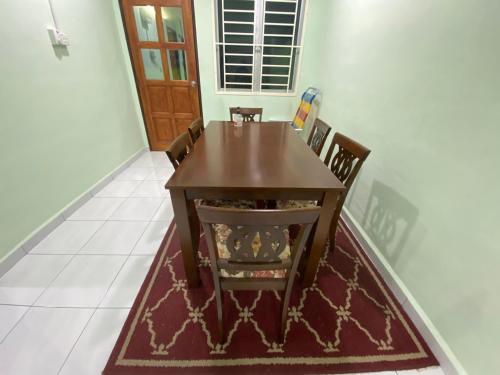 a dining room with a wooden table and chairs at Green House Homestay in Masjid Tanah