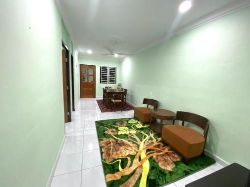 a hallway with a table and chairs and a flower rug at Green House Homestay in Masjid Tanah