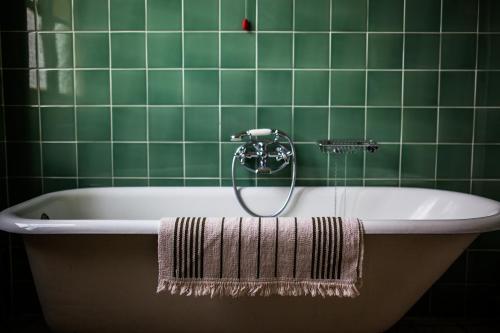 a green tiled bathroom with a bath tub with a shower at Villa Moorings in Barga