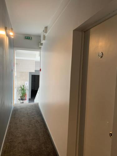 a hallway with a white wall and a door at Hôtel & Restaurant Le Patio VICHY in Vichy