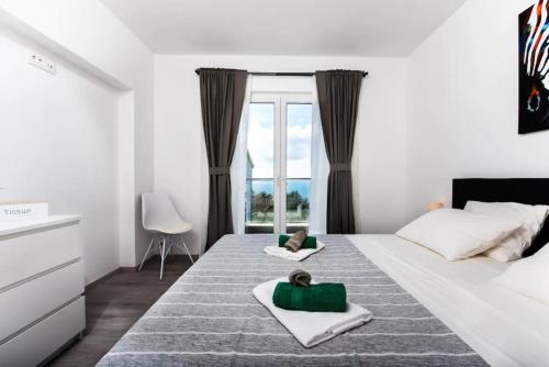 una camera bianca con un grande letto con finestra di Premium holiday home Maslina in Podstrana a Podstrana