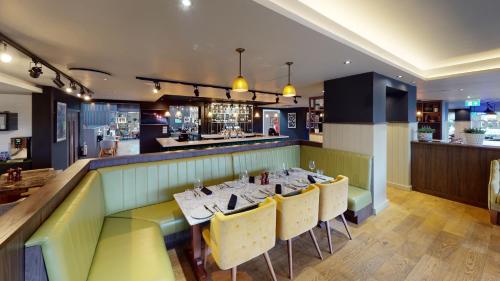 a dining room with a table and yellow chairs at Holiday Inn Milton Keynes Central by IHG in Milton Keynes