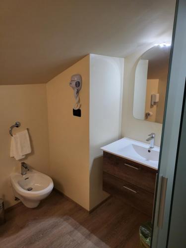 uma casa de banho com um lavatório, um WC e um espelho. em Hotel Miage em Aosta
