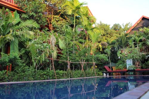 a pool in front of a resort with palm trees at Bou Savy Guesthouse in Siem Reap