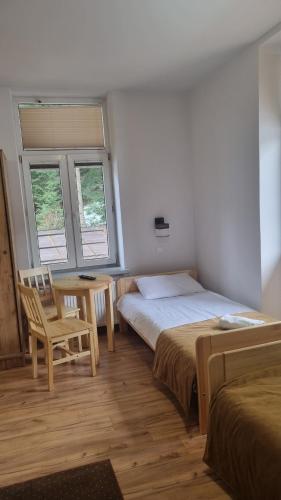 a bedroom with two beds and a table and a chair at HUZAR in Krynica Zdrój