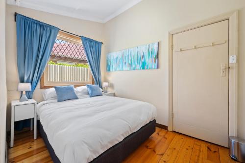 a bedroom with a bed with blue curtains and a window at Swainson on Coombe in Woodville