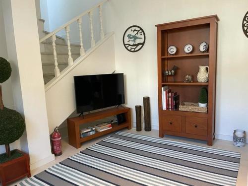 uma sala de estar com televisão e uma escadaria em House with a view em Alcácer do Sal