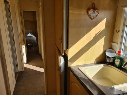 a small bathroom with a sink and a hallway at 6 Berth central heated The Grange (Balmoral II) in Ingoldmells