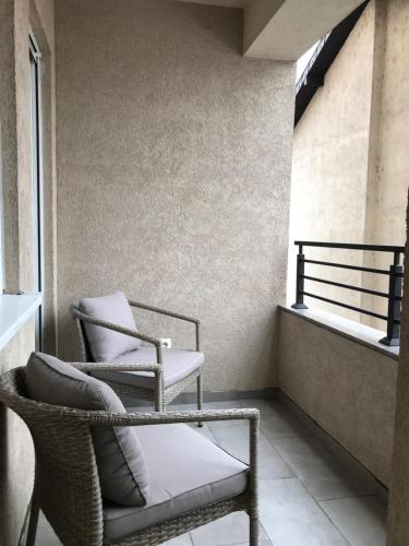 2 sillas sentadas en un balcón con ventana en Green Apartment en Novi Pazar