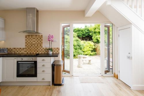 a kitchen with an open door leading to a patio at New House, " Orchard Croft Lodge ", DOG FRIENDLY, 20 Minutes From Goodwood Events, 9 Minutes From Sandy West Wittering Beach, 2 Bathrooms, Can Sleep 8 On Request, Free Wi-Fi & Sky Sports, Very Quiet Location, Free Parking for 8 Cars in Chichester