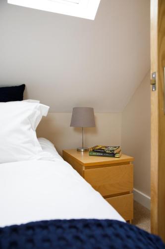 a bedroom with a bed and a lamp on a night stand at New House, " Orchard Croft Lodge ", DOG FRIENDLY, 20 Minutes From Goodwood Events, 9 Minutes From Sandy West Wittering Beach, 2 Bathrooms, Can Sleep 8 On Request, Free Wi-Fi & Sky Sports, Very Quiet Location, Free Parking for 8 Cars in Chichester