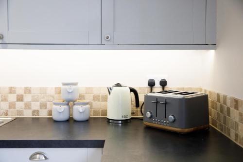 a kitchen counter with a toaster and a coffee maker at New House, " Orchard Croft Lodge ", DOG FRIENDLY, 20 Minutes From Goodwood Events, 9 Minutes From Sandy West Wittering Beach, 2 Bathrooms, Can Sleep 8 On Request, Free Wi-Fi & Sky Sports, Very Quiet Location, Free Parking for 8 Cars in Chichester
