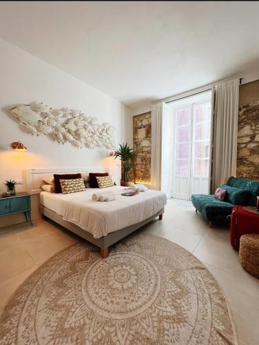 a bedroom with a bed and a couch and a rug at Calamùrn Ortigia in Siracusa