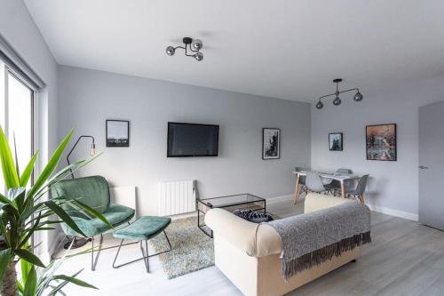 a living room with a couch and chairs and a tv at Causeway Coast Beach Front Apartment - Ballycastle in Ballycastle