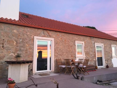 a stone house with a table and chairs in front of it at Casa Trilhos da Serra in Alcobertas