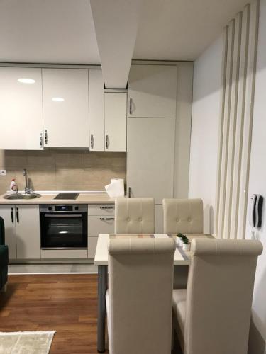 cocina con armarios blancos, mesa y sillas en Green Apartment, en Novi Pazar