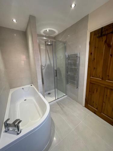 a bathroom with a bath tub and a shower at Merlin House in Wrexham