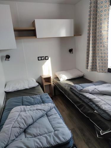une chambre avec deux lits et une fenêtre dans l'établissement Assist' Mobil home 363 - Charmant mobil home 8 personnes 3 chambres, à Onzain