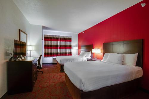 a hotel room with two beds and a red wall at Inn at Hunters Run in Watford City