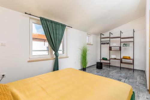een slaapkamer met een geel bed en een raam bij Apartman Nina in Fažana