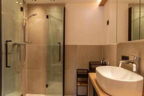 a bathroom with a shower and a white sink at Apartment LISAL by All in One Apartments in Bruck an der Großglocknerstraße