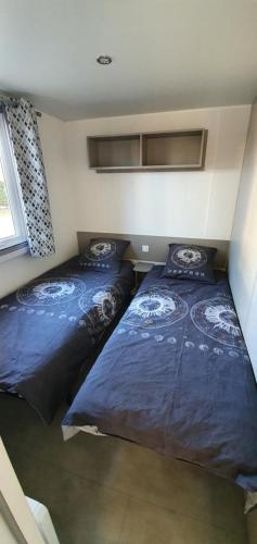 two beds in a room with blue comforters at MH 149 4 pers camping Bois Dormant confort et détente in Saint-Jean-de-Monts