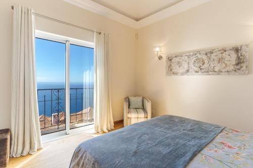 Villa Bougainvillea Palheiro Village by HR Madeira في فونشال: غرفة نوم بسرير ونافذة كبيرة