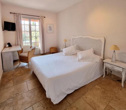 a bedroom with a large white bed and a desk at Castillon Des Baux in Maussane-les-Alpilles