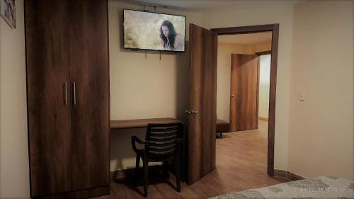 Zimmer mit einem Tisch und einem TV an der Wand in der Unterkunft Apart Cayambe in Cayambe