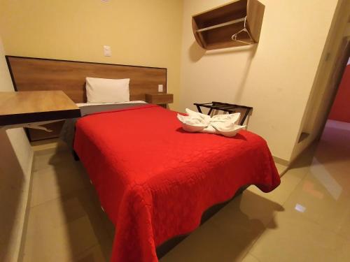 a bedroom with a red bed with two white shoes on it at HOTEL SAN JOSE in San Martín Texmelucan de Labastida