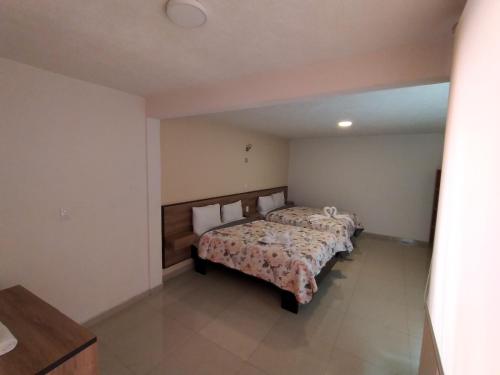 a bedroom with two beds and a table in it at HOTEL SAN JOSE in San Martín Texmelucan de Labastida