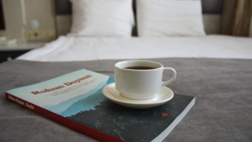 a cup of coffee sitting on a book on a bed at Temizay Hotel in Canakkale