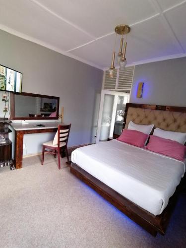 a bedroom with a large bed and a desk at Adirondack Inn in Estcourt