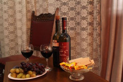 a table with two glasses of wine and a plate of grapes at Hotel Tskhumi in Kutaisi