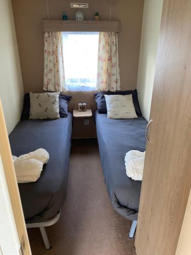 two beds in a small room with a window at DaisyChain 2 Getaways - The perfect place to Stay - Play - Getaway in East Mersea