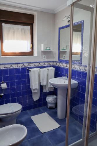 a blue tiled bathroom with a toilet and a sink at Apartamentos Casa Bernabé in Miengo