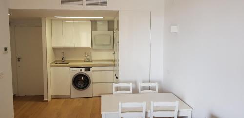 een keuken met een wasmachine en een tafel en stoelen bij CHINASOLYMAR LUXURY - Con Parking in Almuñécar