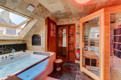 een badkamer met een groot bad en een raam bij SOUS MON TOI Topdestination-Dijon - Sauna & jacuzzi - Classé 3 étoiles in Dijon