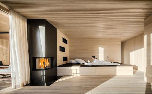 a woman laying in a bed in a room with a fireplace at Ferienhaus Bergfrieden Laterns auf 1.170 m in Laterns