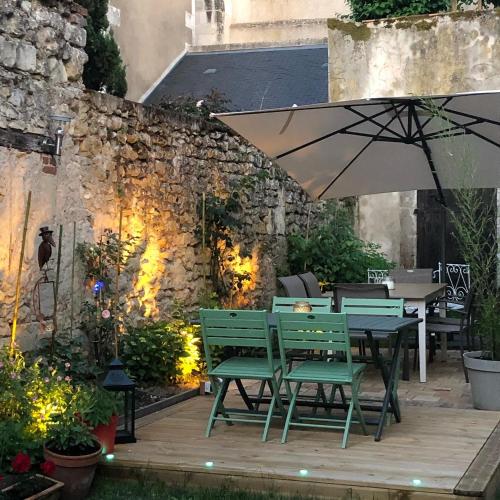 a patio with a table and chairs and an umbrella at Les 3 échoppes in Chargé