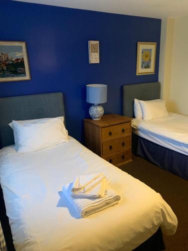 a hotel room with two beds and a night stand with towels at The Barrington Arms Hotel in Shrivenham