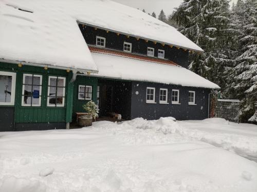a house covered in snow in front of it at Somewhere Elz - Luxus Chalet für bis zu 38 Gäste in Elzach