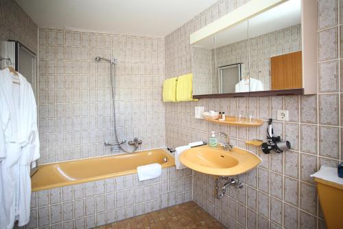 a bathroom with a yellow tub and a sink at Landgasthof Rebstock in Sulzburg