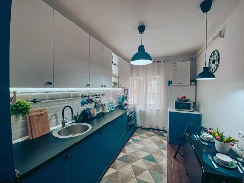 a kitchen with blue cabinets and a sink and a refrigerator at Apartment One Brasov in Braşov